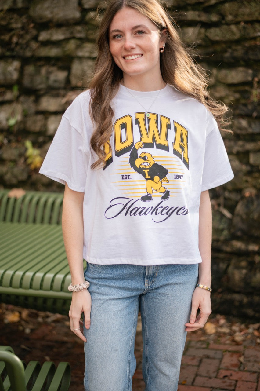 Woman wearing a white 'Iowa Hawkeyes' women's easy t-shirt with a brick wall background