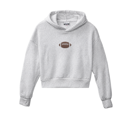 A light heather gray cropped hoodie sweatshirt featuring a small brown American football graphic printed on the center chest, displayed against a solid white background.